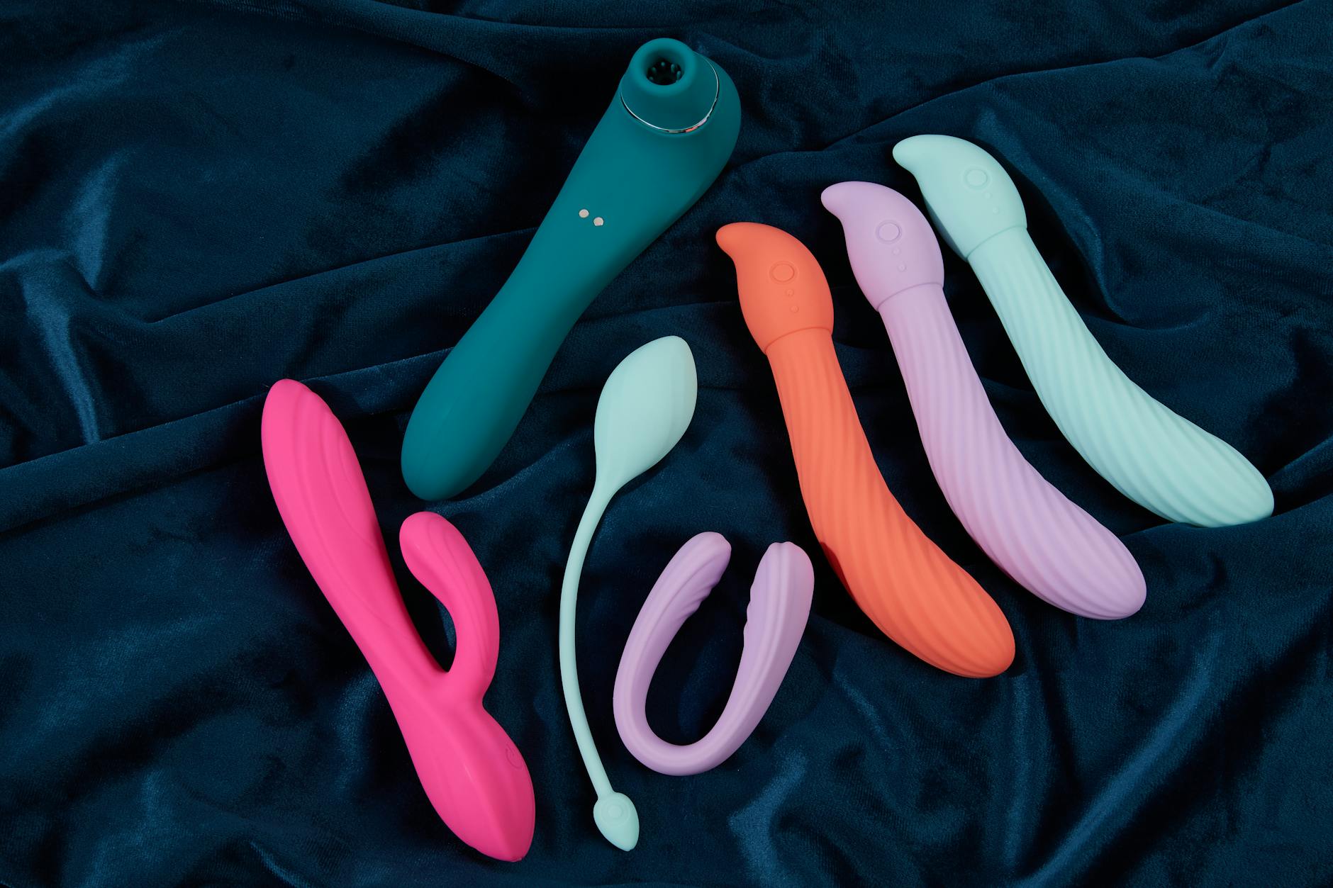 Collection of silicone vibrators in various colors arranged on dark blue fabric