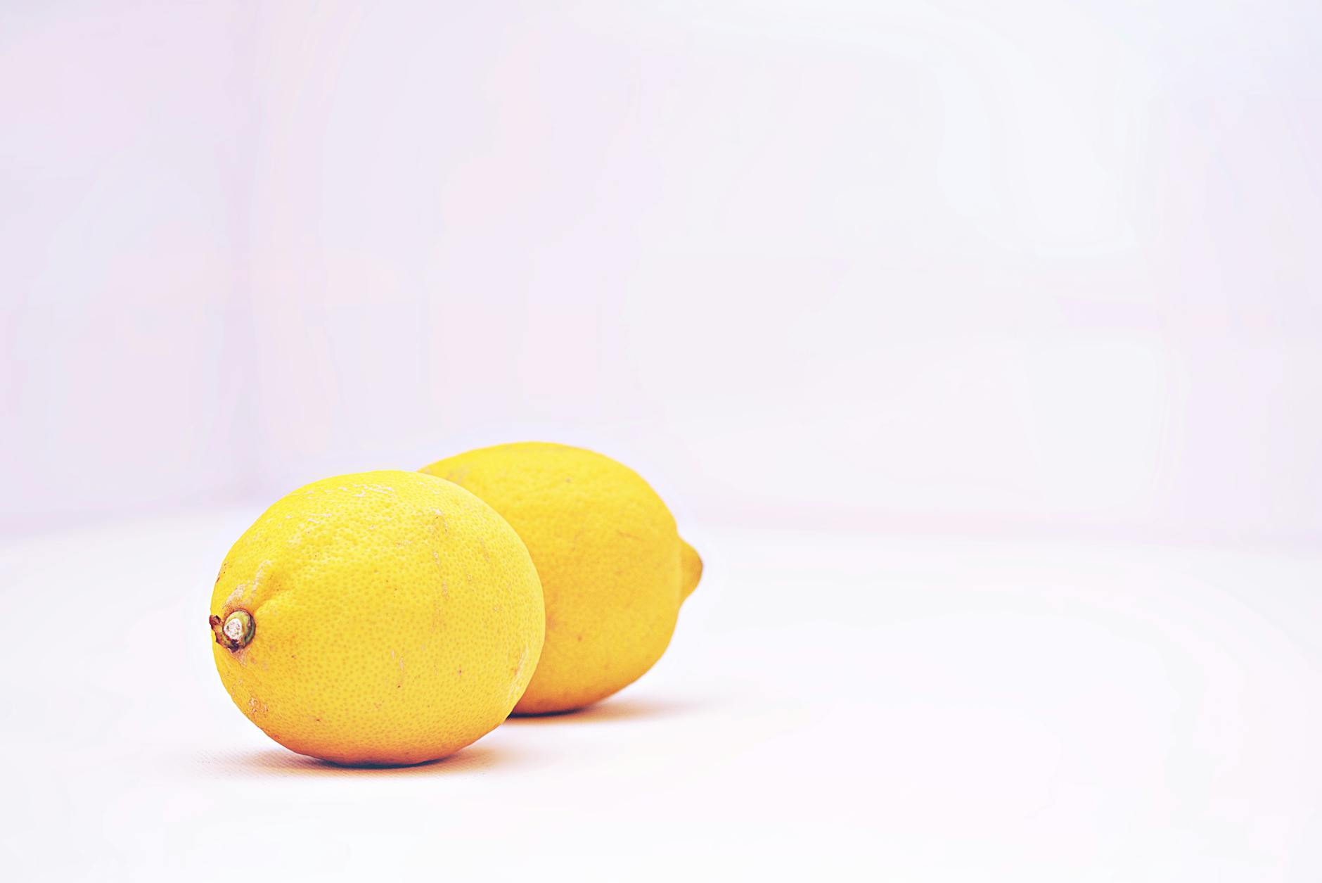 Two vibrant lemons against a minimalistic white background, symbolizing fresh approaches to pleasure and sensation.