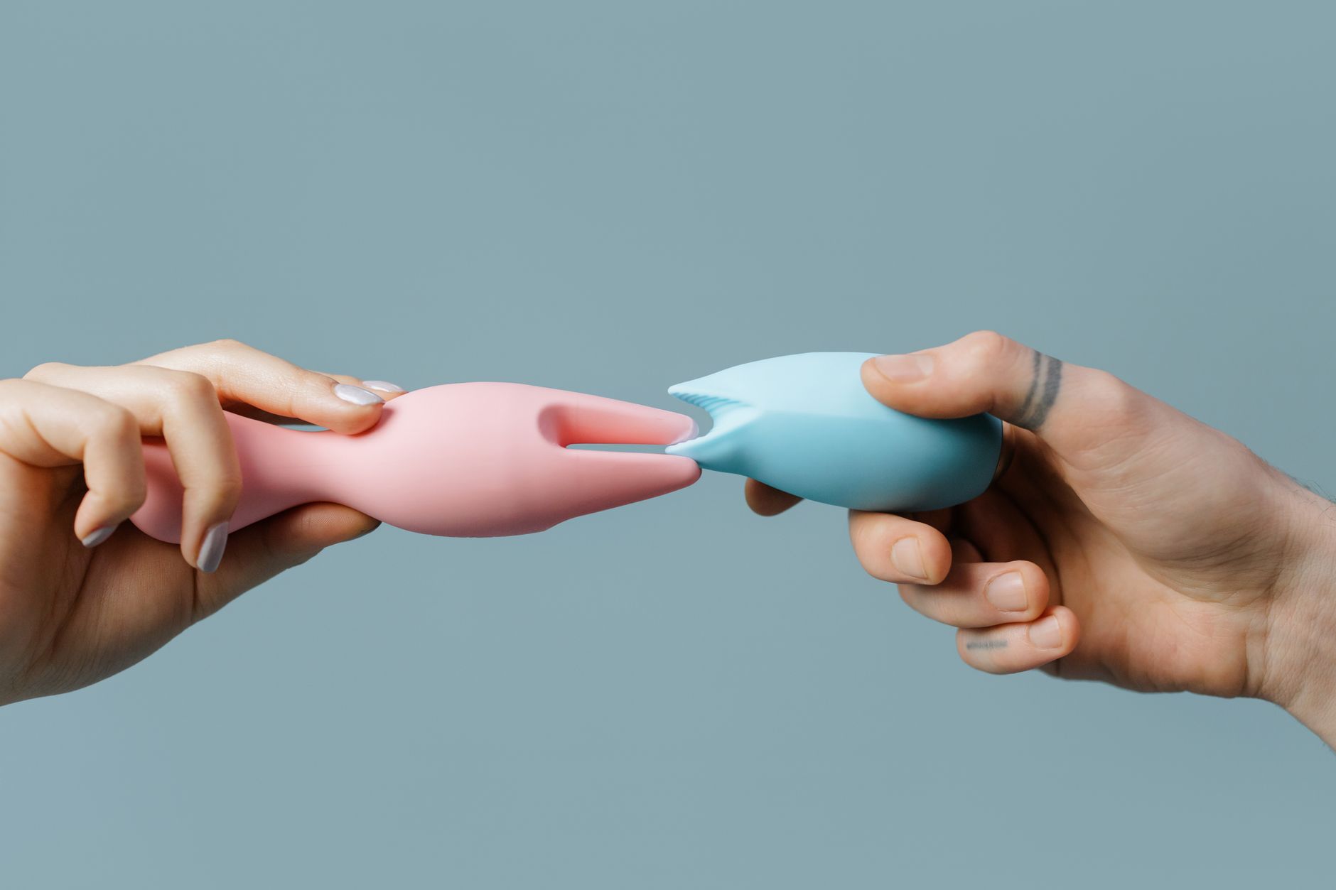 Hand holding an orange vibrator against a purple backdrop