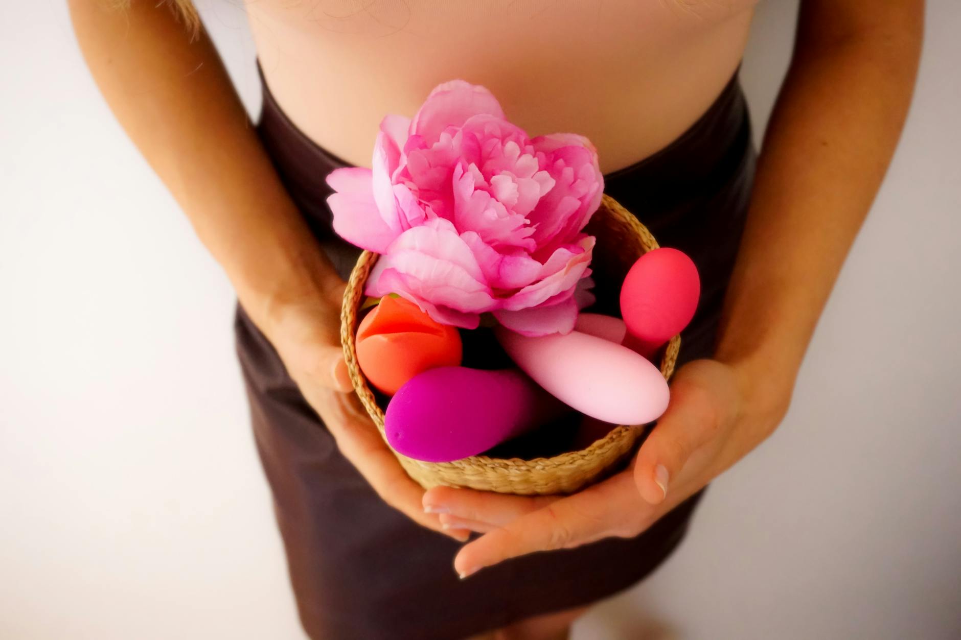 Close-up of hands holding a lemon vibrator against a knitted sweater, intimate and tactile